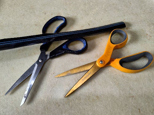 Pairs of scissors near a pipe.