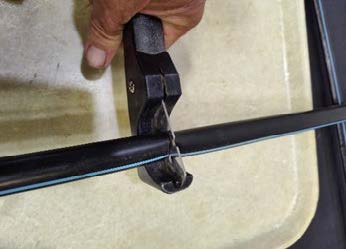 Tube cutter cutting polyethylene irrigation tubing.