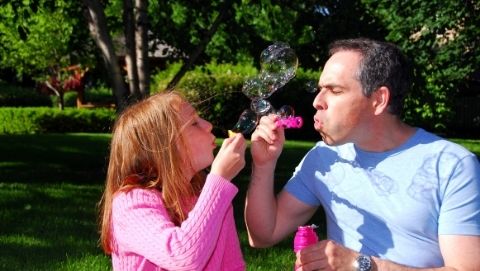 dad and girl blowing bubbles together