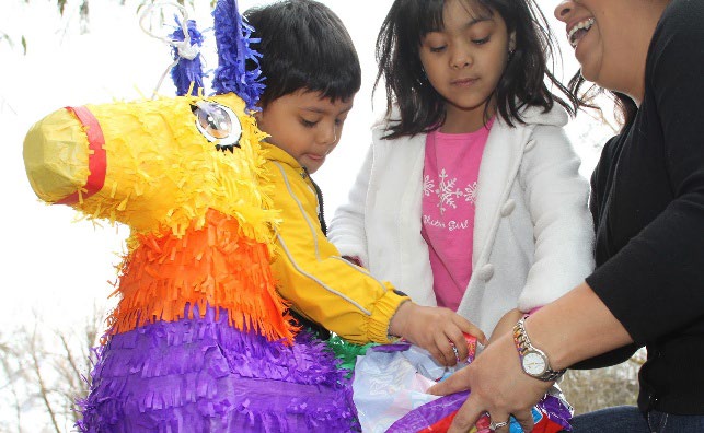 Children putting candy in a pinata.