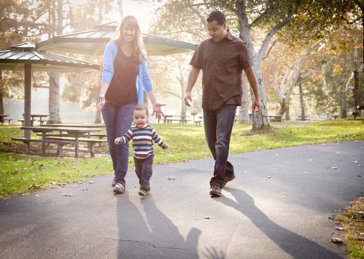 A small family walking on an outdoor path.