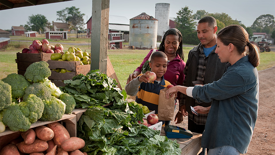family purchasing produce at farm stand