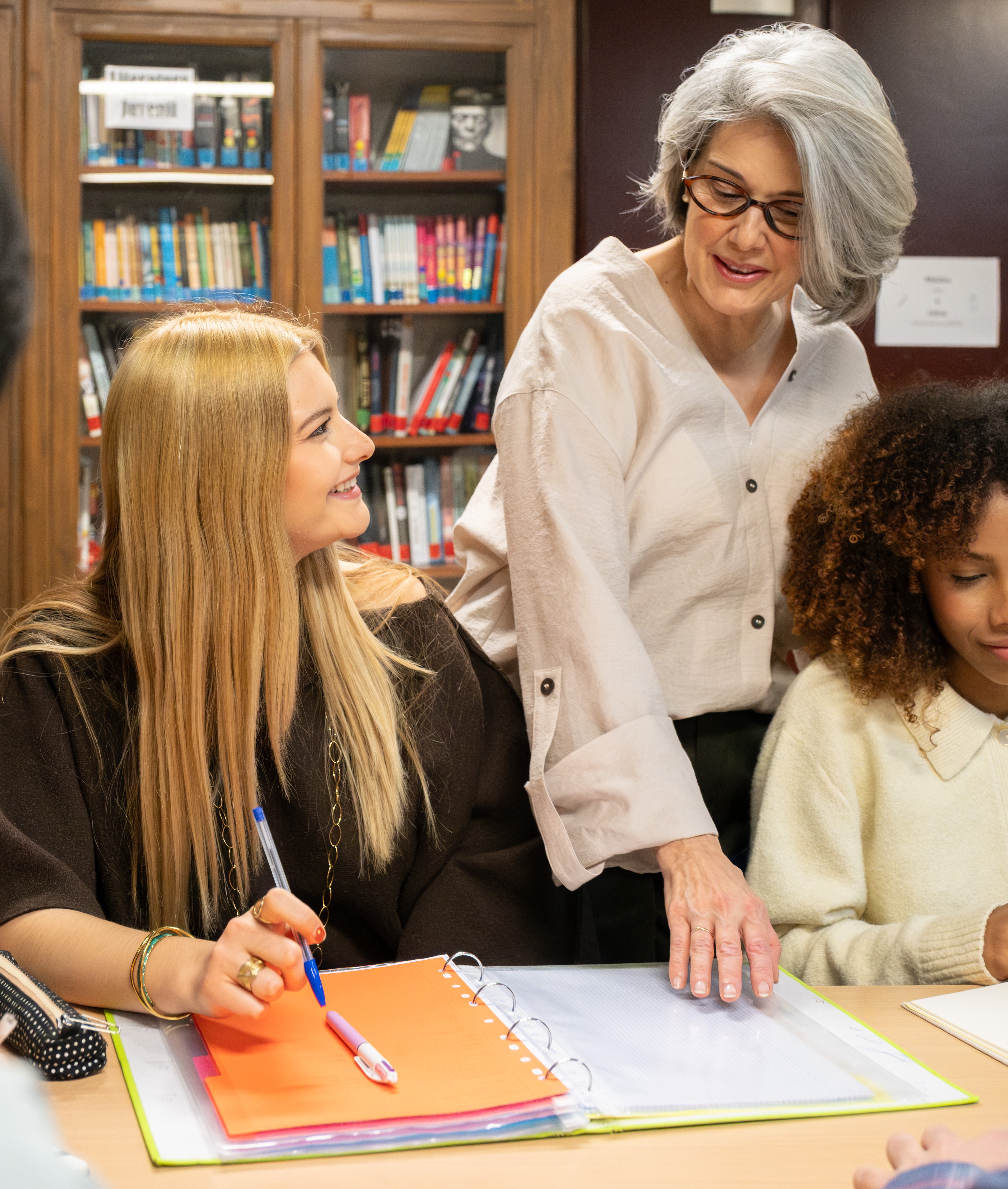 Teacher in a classroom interacting with a smiling teenage student.
