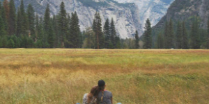 Couple in mountain meadow, woman has head on a man's shoulder