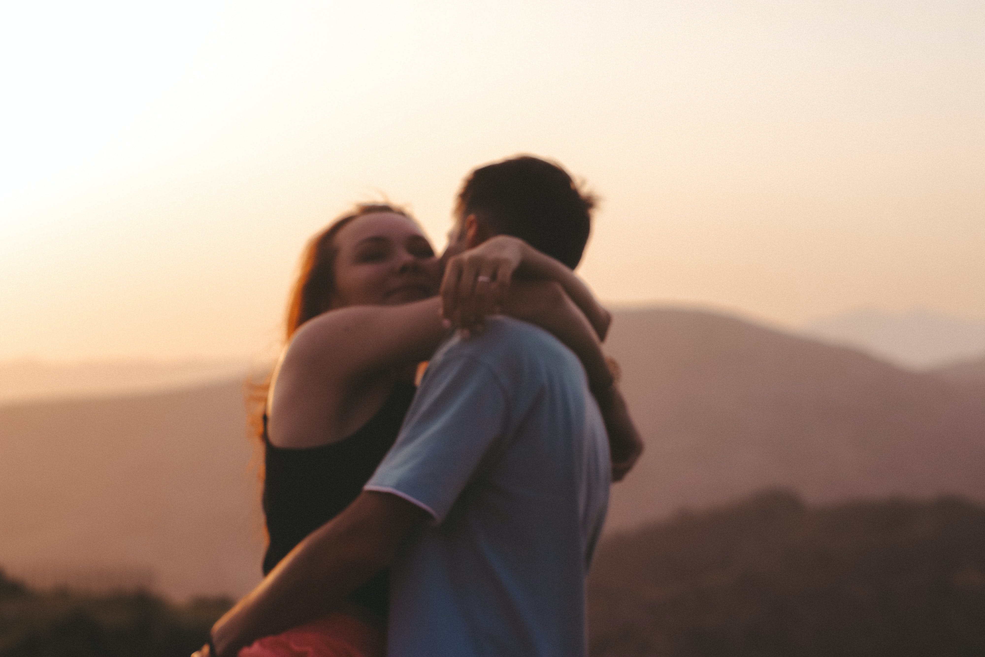 man and woman hugging in front of beautiful sunset