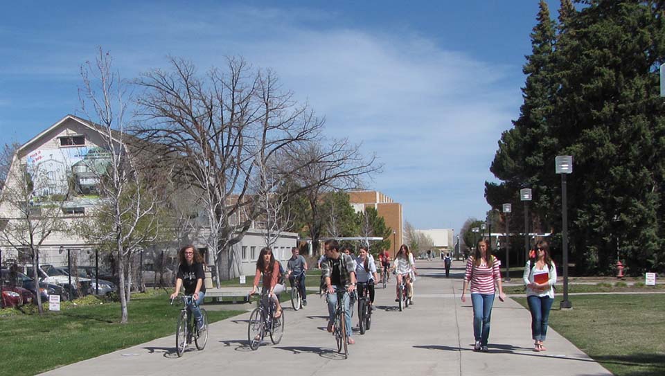 Students walking and riding bikes on USU campus sidewalk