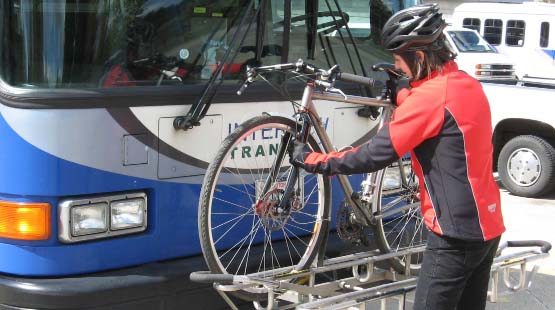 Cyclist mounting bike on front of a commuter bus