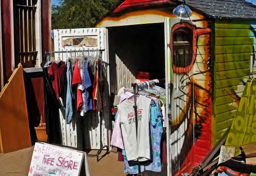 Items on racks outside a colorfully painted trailer with a sign that says 'free store'