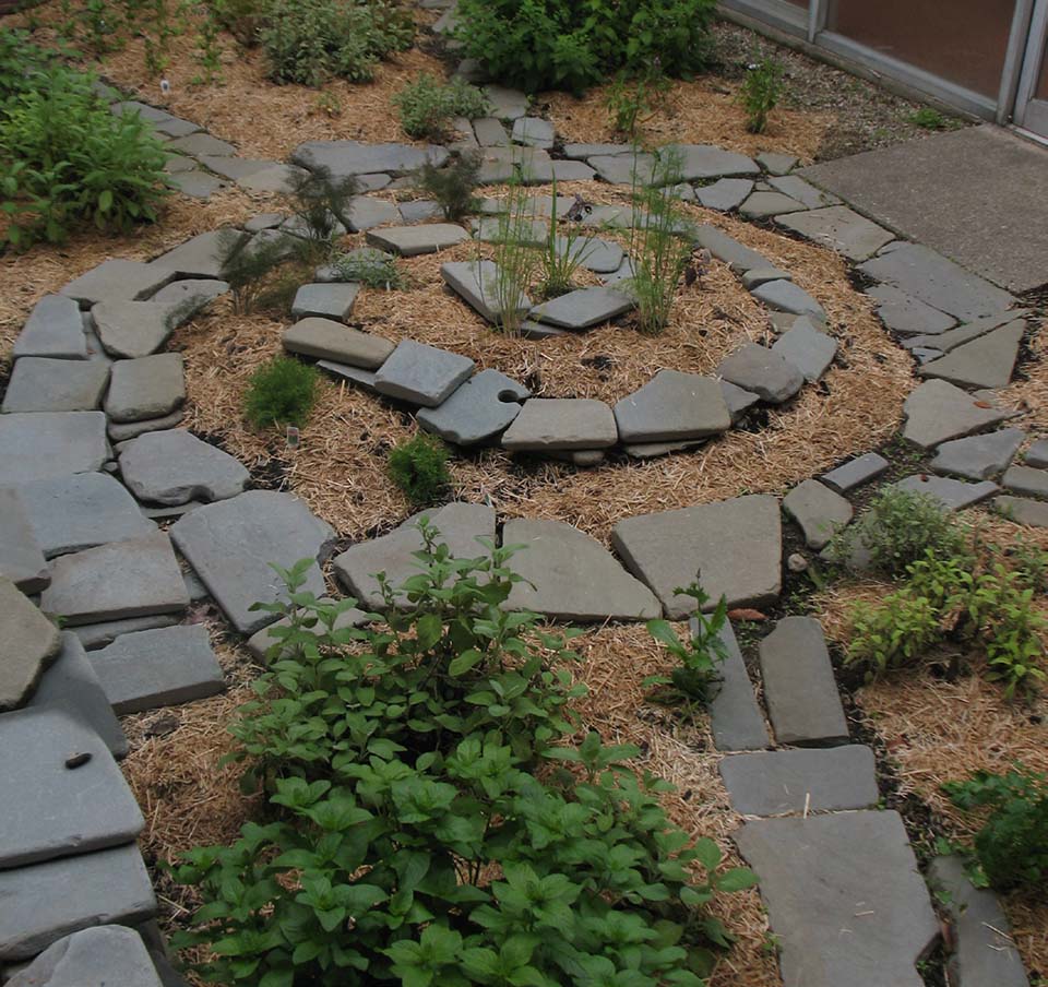 Mulch garden bed with spirals of herbs and stone borders