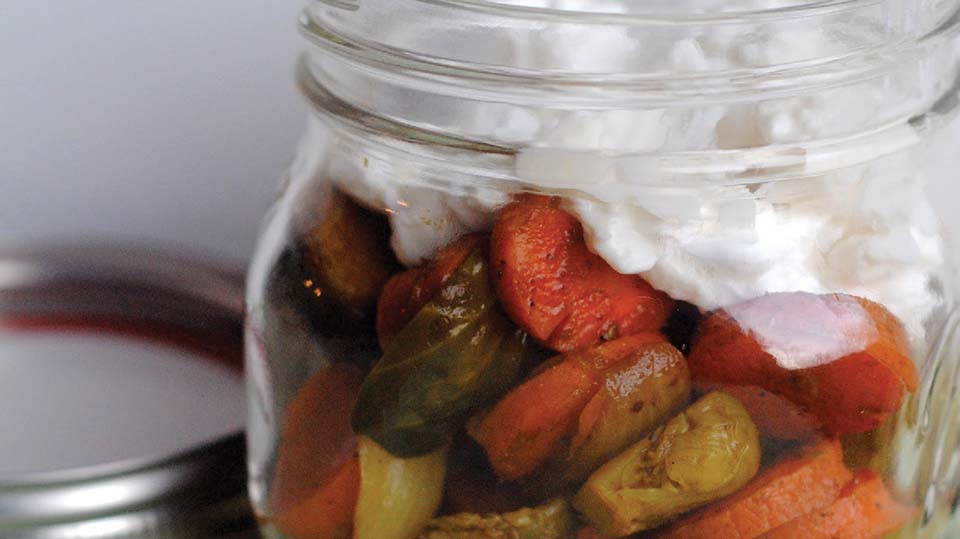 Mason jar filled with cooked vegetables and cream or sauce