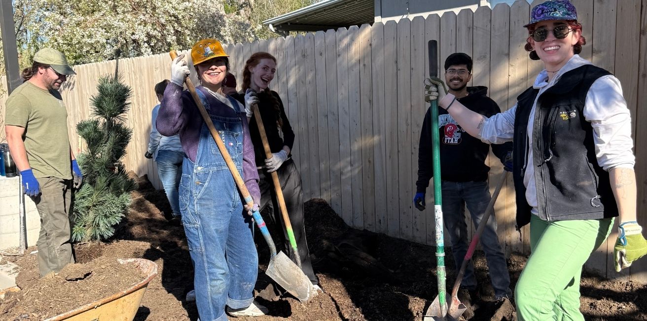 A group of young adults with shovels digging in the soil