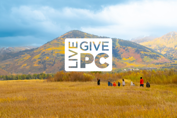 group of people walking on nature preserve during the fall with orange and yellow mountains in the background. Live PC Give PC logo is overlaid on top.