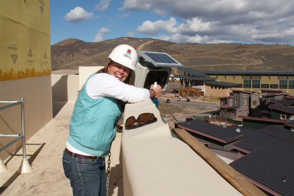 woman wearing hard hat and standing near construction site