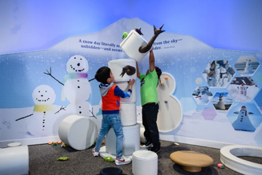 kids building a faux snowperson in an exhibit