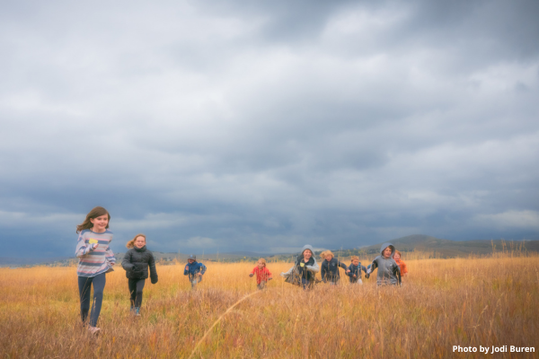 Kids running in a wetland field with moody clouds above