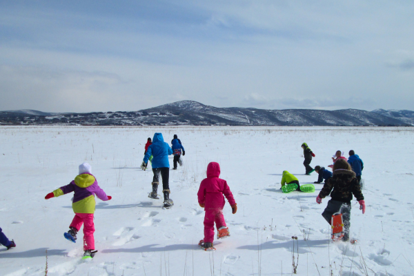 Kids running in snow shoes across field