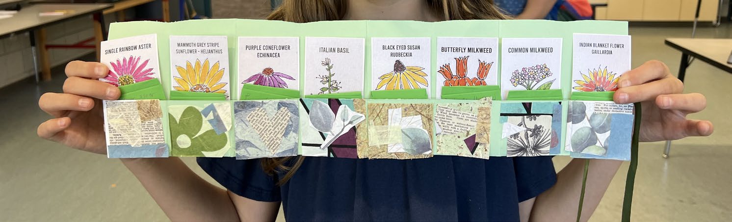 Person holding a handmade accordion-style booklet displaying illustrated seed packets for different flowers and plants, with decorative collage panels underneath each packet.