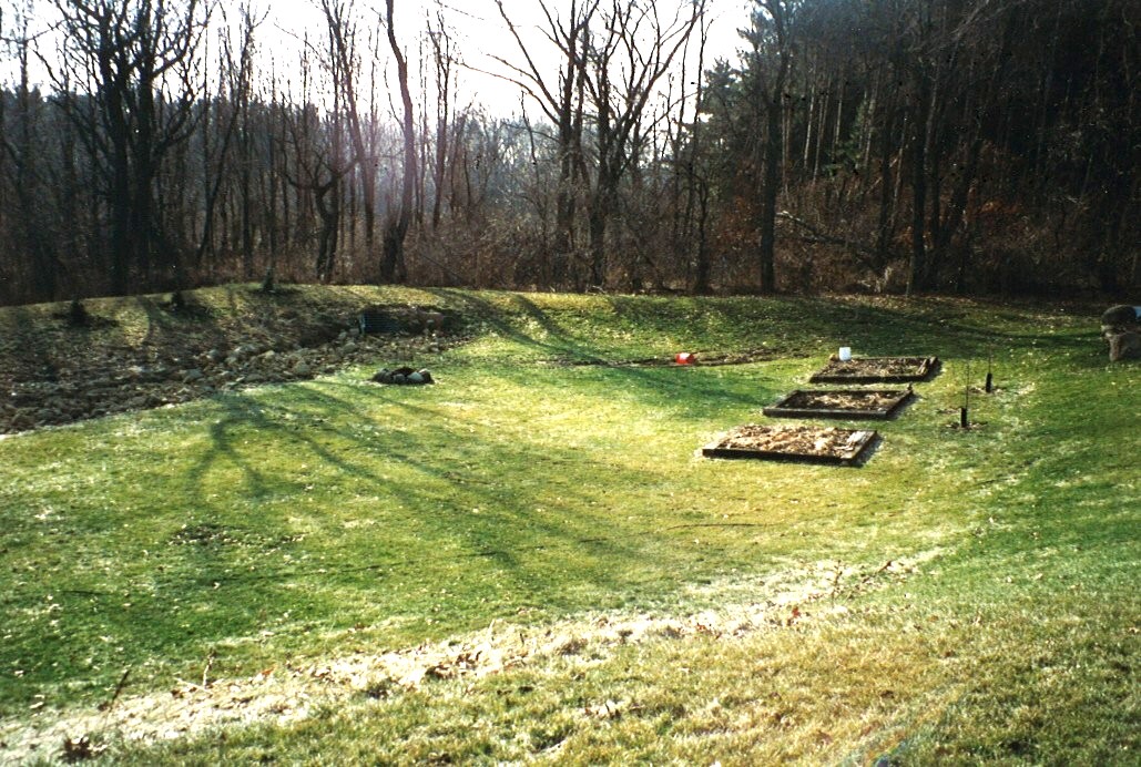An area of grass in an opening of trees with berms.