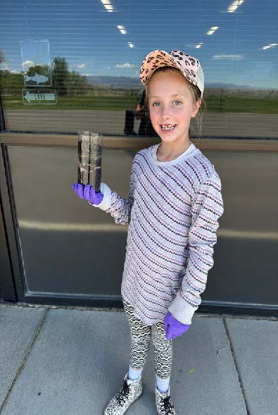 A young girl holding a jar of compost.