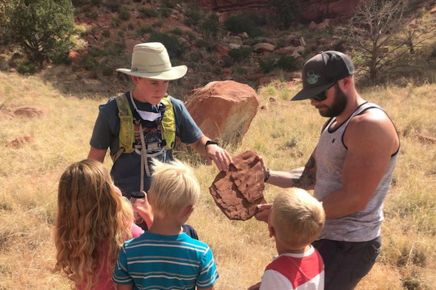 Two adults show a rock sample to some children