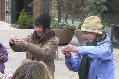 Two people hold up and show objects to a group of observers