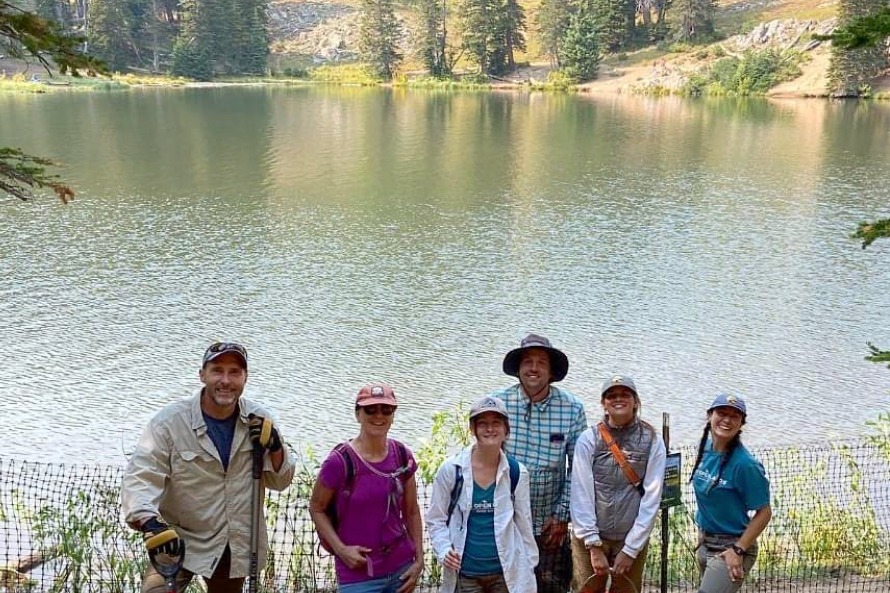 A group of people pose in front of a mountain lake