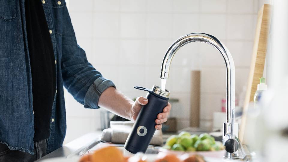 man filling water bottle at a faucet
