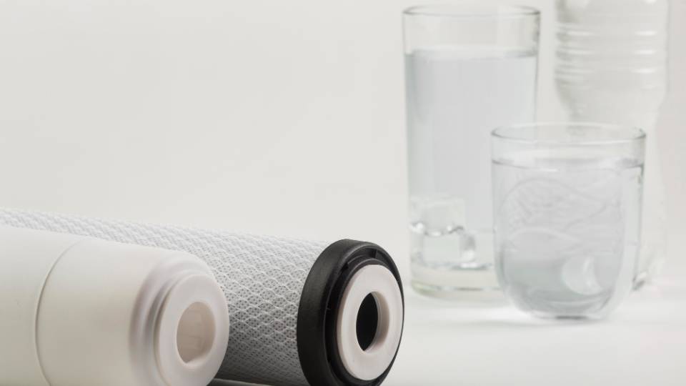 three glasses of water next to pieces of a water filter