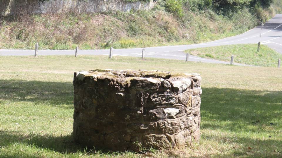 a stone well with a road and grass